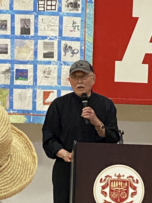Lawson Inada speaks behind a podium in the school